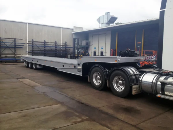 Tri-axle TSA-50 heavy-duty equipment trailer with full-length flat deck, parked at yard