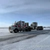 TSA-50 heavy trailer moving a tractor truck across a snowy highway during winter conditions