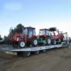 TSA-50 heavy-duty trailer transporting multiple compact farm tractors on a dirt lot