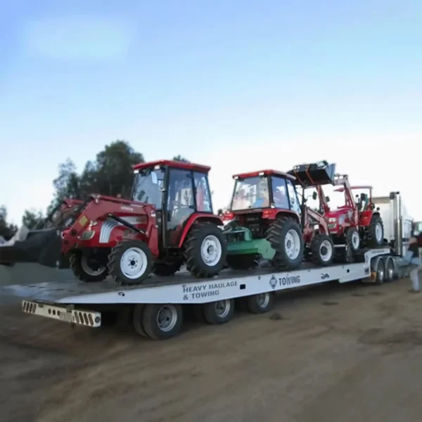 TSA-50 heavy-duty trailer transporting multiple compact farm tractors on a dirt lot