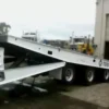 Side view of a TSA-50 tilt deck trailer partially lowered at a warehouse loading bay
