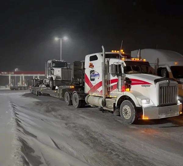 TSA-50 trailer hauling a tractor truck during nighttime on a snowy road
