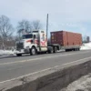 Highway shot of TSA-50 equipment trailer hauling a loaded shipping container through snowy conditions