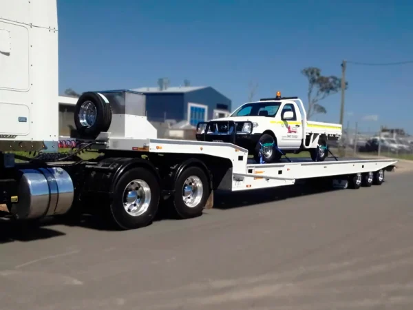 Side view of TSA-50 trailer transporting a medium-duty tow truck, showing deck strength and axle setup