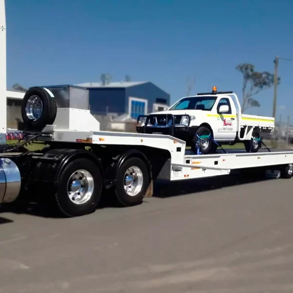 Side view of TSA-50 trailer transporting a medium-duty tow truck, showing deck strength and axle setup