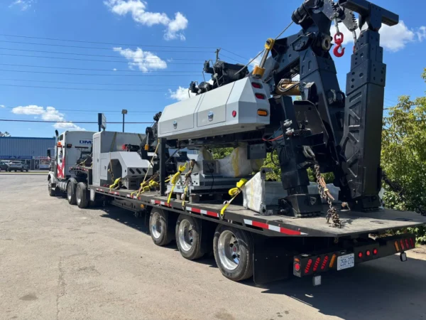 STT-50 heavy-haul trailer carrying a detachable towing unit and wrecker body, secured with chains and straps