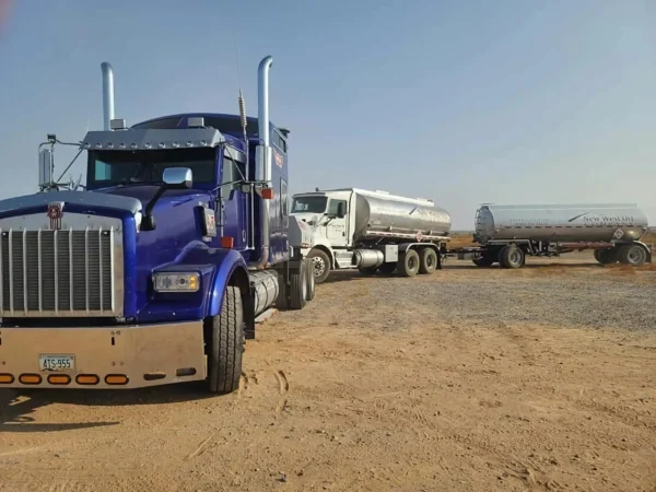 Blue MDTU-20 detachable tow unit recovering a dump truck in sandy terrain, underlift in use