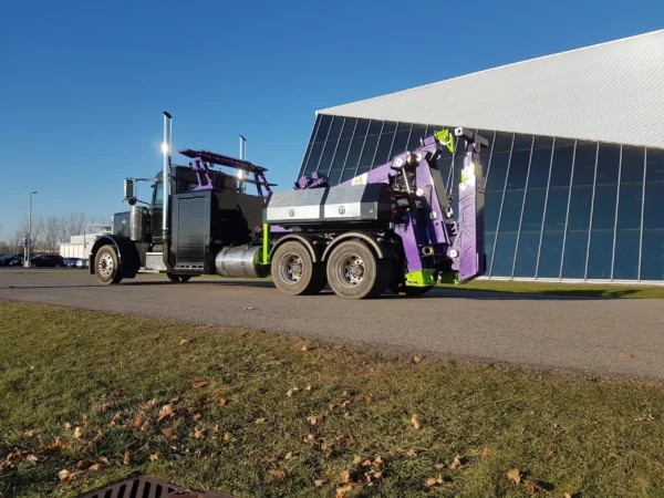 MDTU-20 wrecker body engaged in lift position, truck parked near industrial glass building