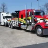 Red RTR-25 rotator heavy wrecker transporting a damaged tractor-trailer