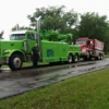 Green RTR-25 rotator tow truck towing dump truck from roadside