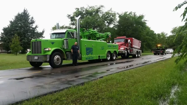Green RTR-25 rotator tow truck towing dump truck from roadside